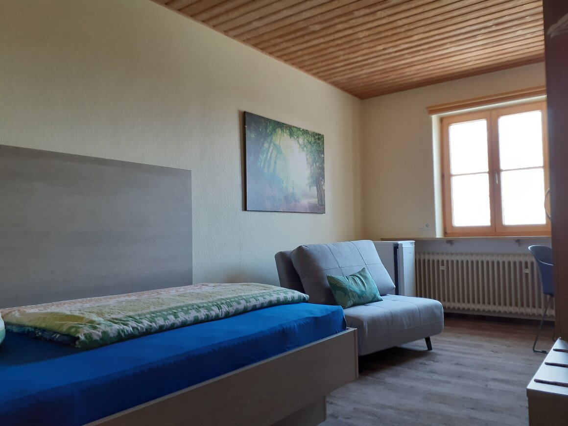 Helles Einzelzimmer mit Bett und Schreibtisch